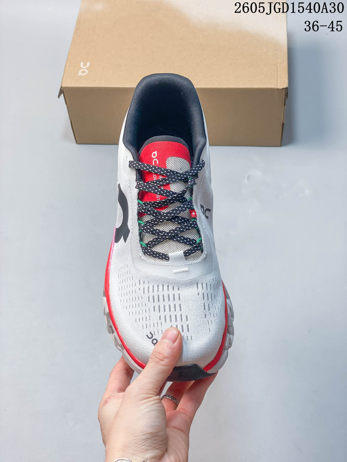 Top view of a white running shoe with patterned laces and a red tongue
