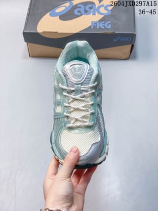 Top view of the ASICS sneaker showing the white laces, layered toe area, and light sage color scheme.