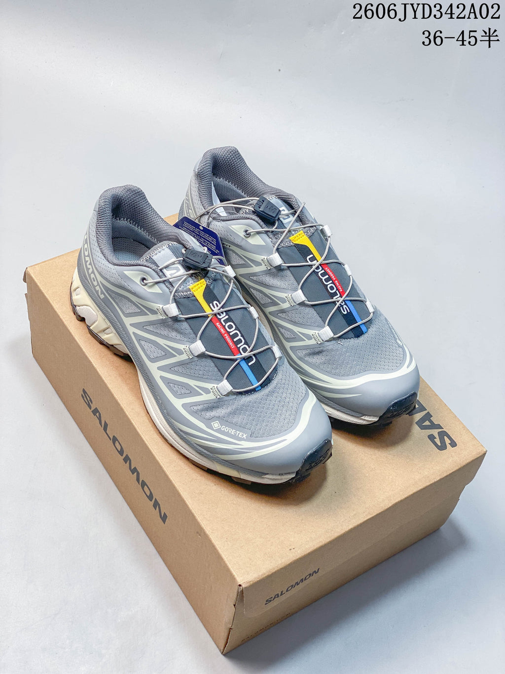 Pair of grey Salomon trail-style shoes with cord lacing and lugged soles on a box