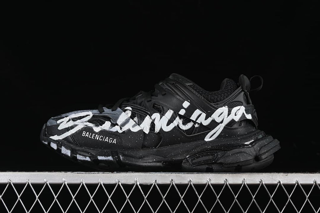 Black Track sneaker with white handwriting-style graphics, shown from the side.