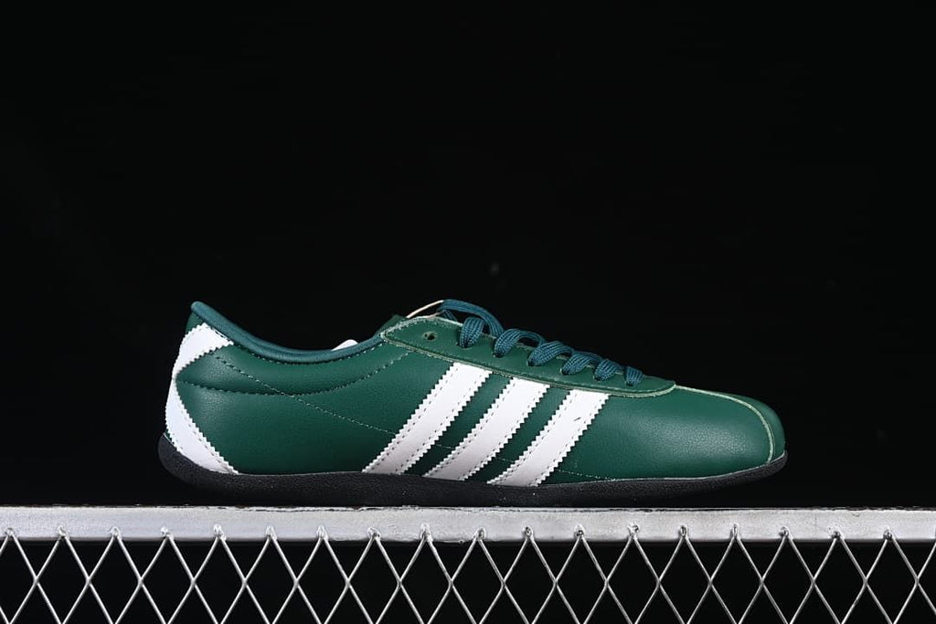 Side profile of the green sneaker with white stripes and a black sole.