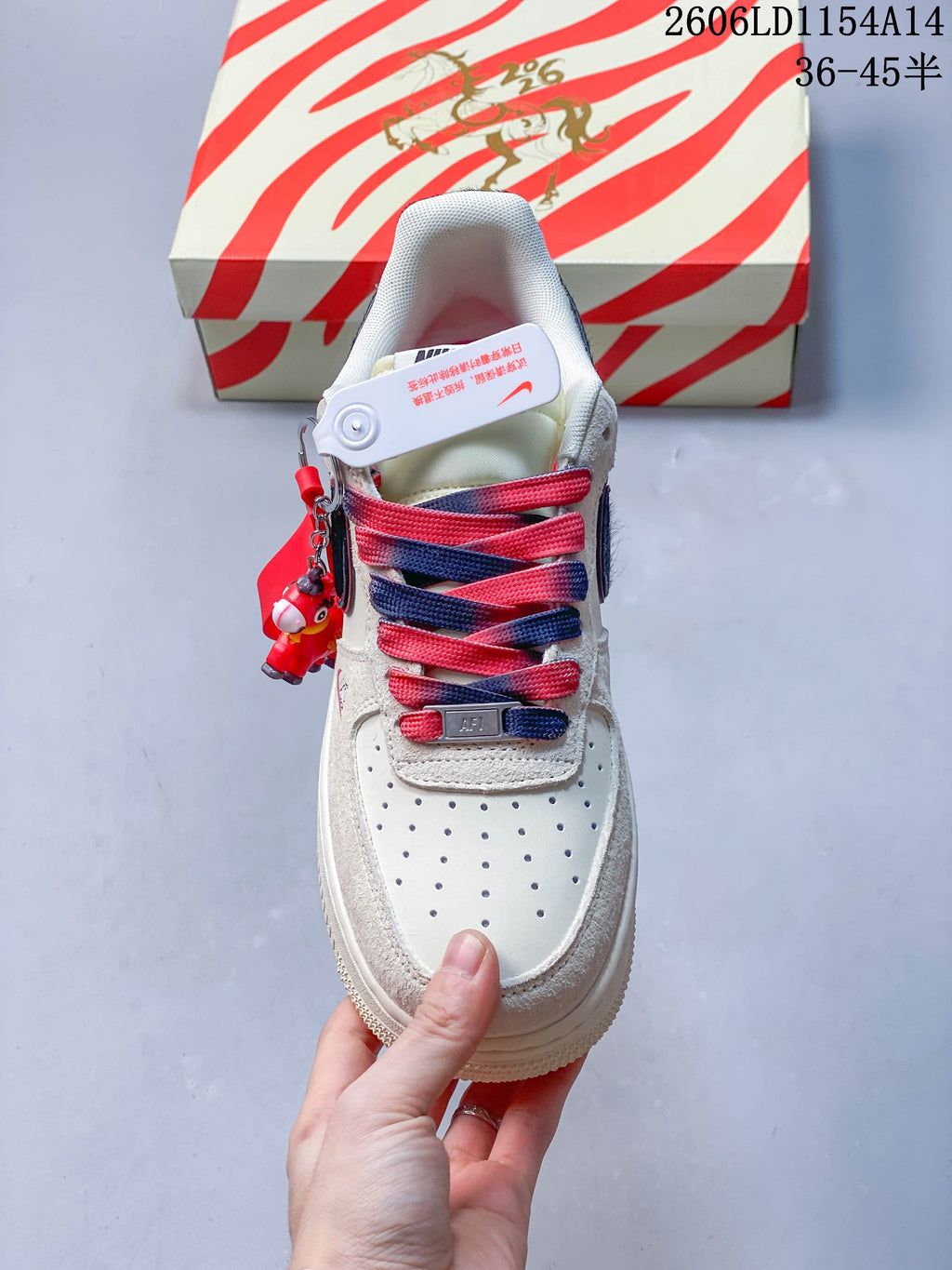Front view of a cream low-top sneaker with red and navy laces
