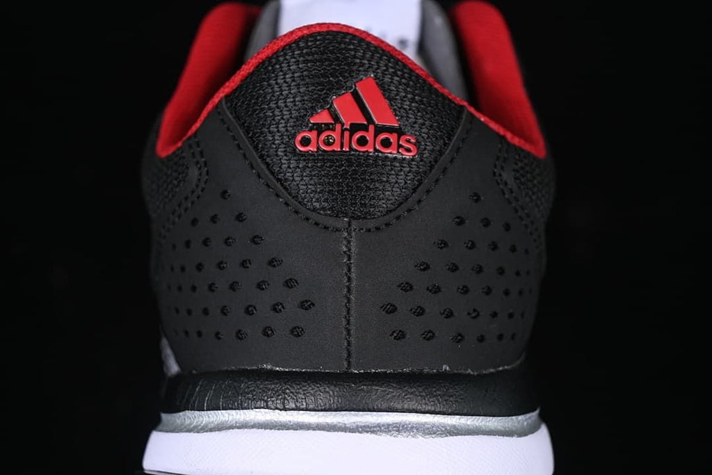 Rear view of the black sneaker with perforated heel panels and red Adidas branding.