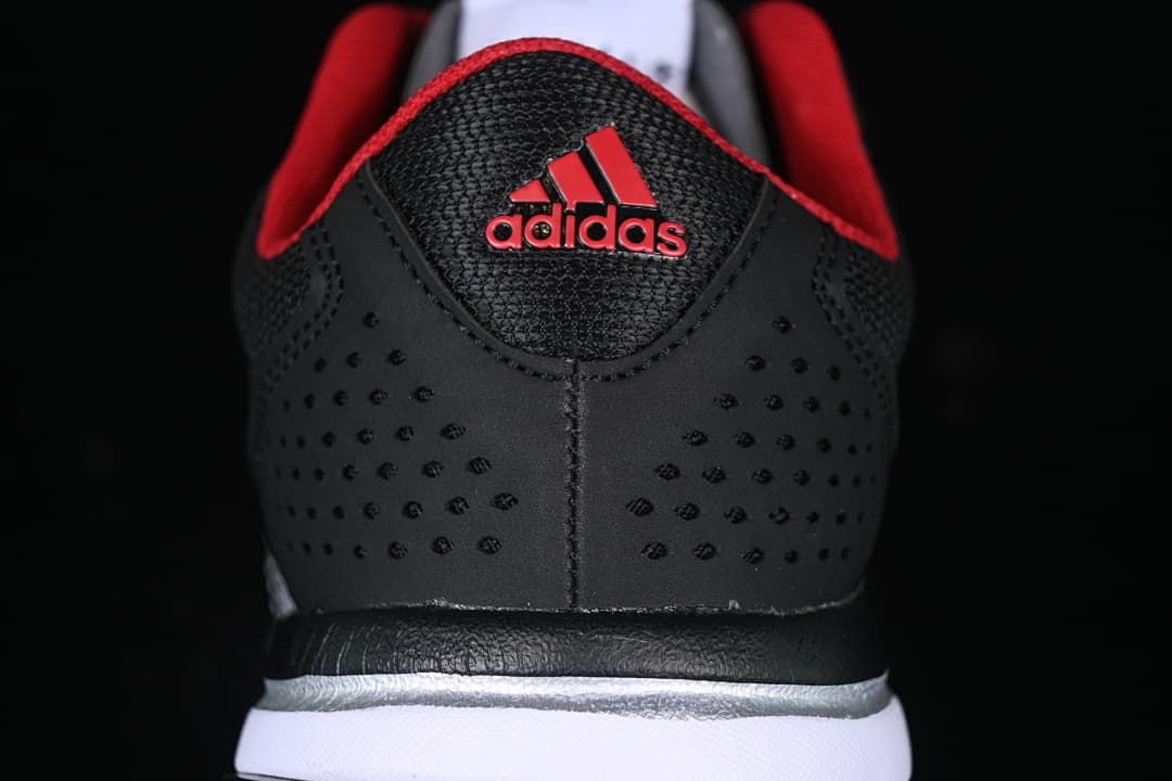 Rear view of the black sneaker with perforated heel panels and red Adidas branding.