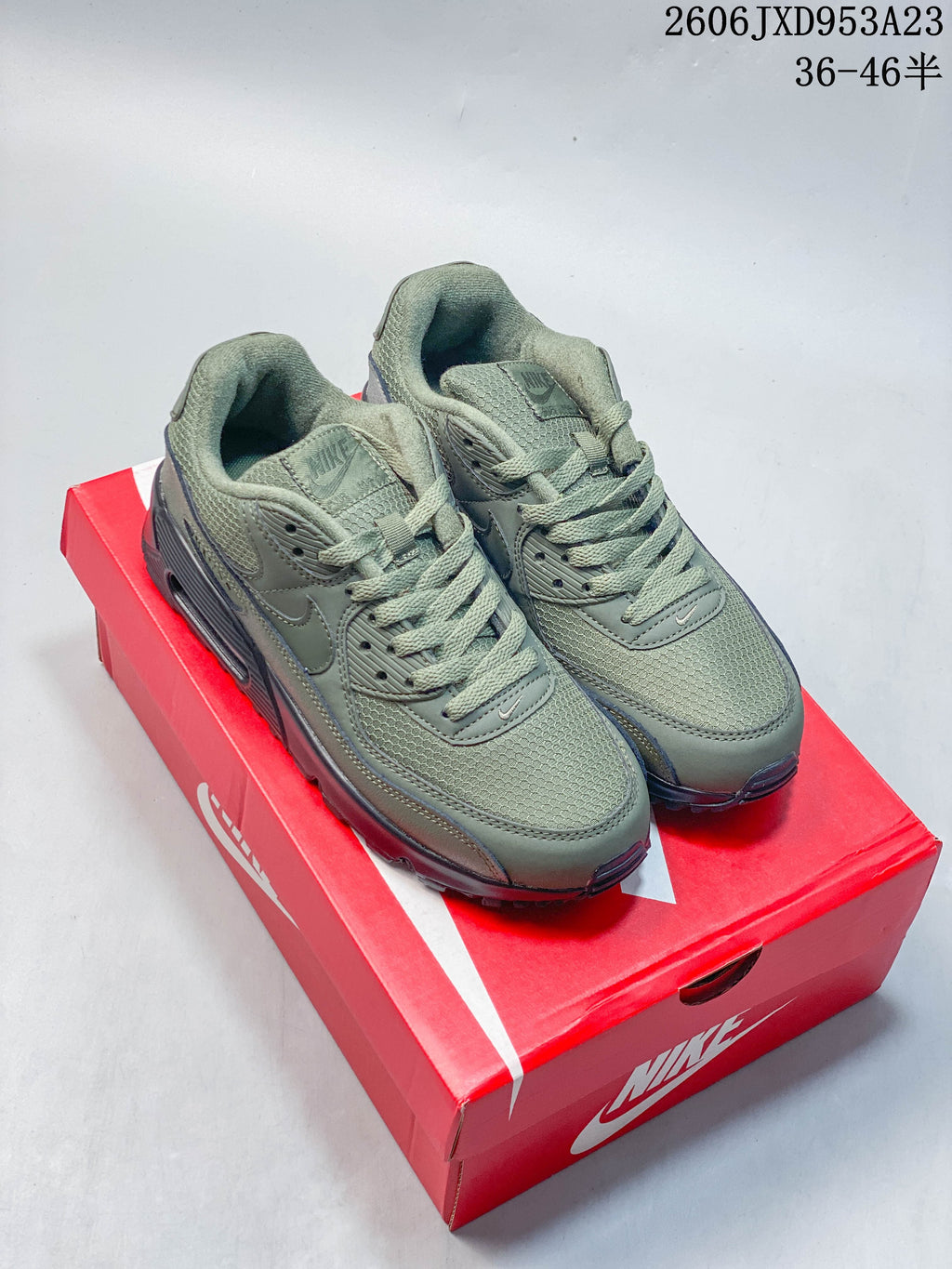 Pair of olive green Nike Air Max 90 sneakers on a red Nike shoe box