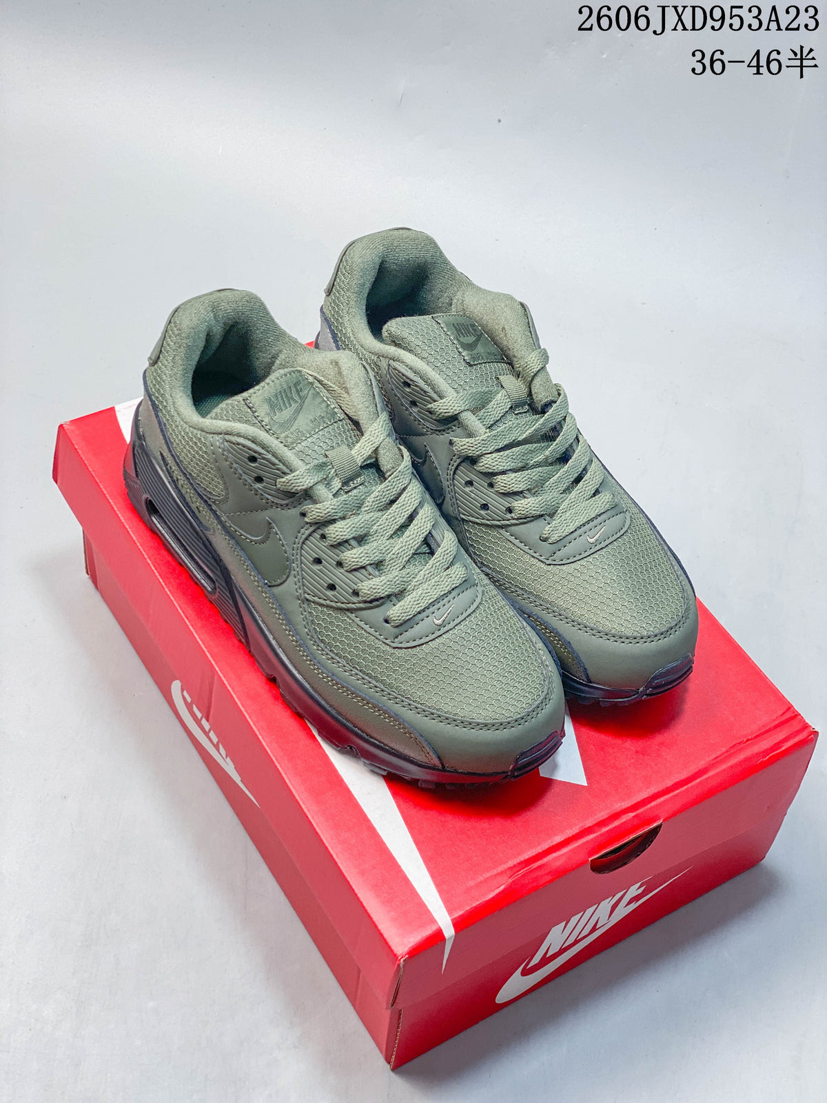 Pair of olive green Nike Air Max 90 sneakers on a red Nike shoe box