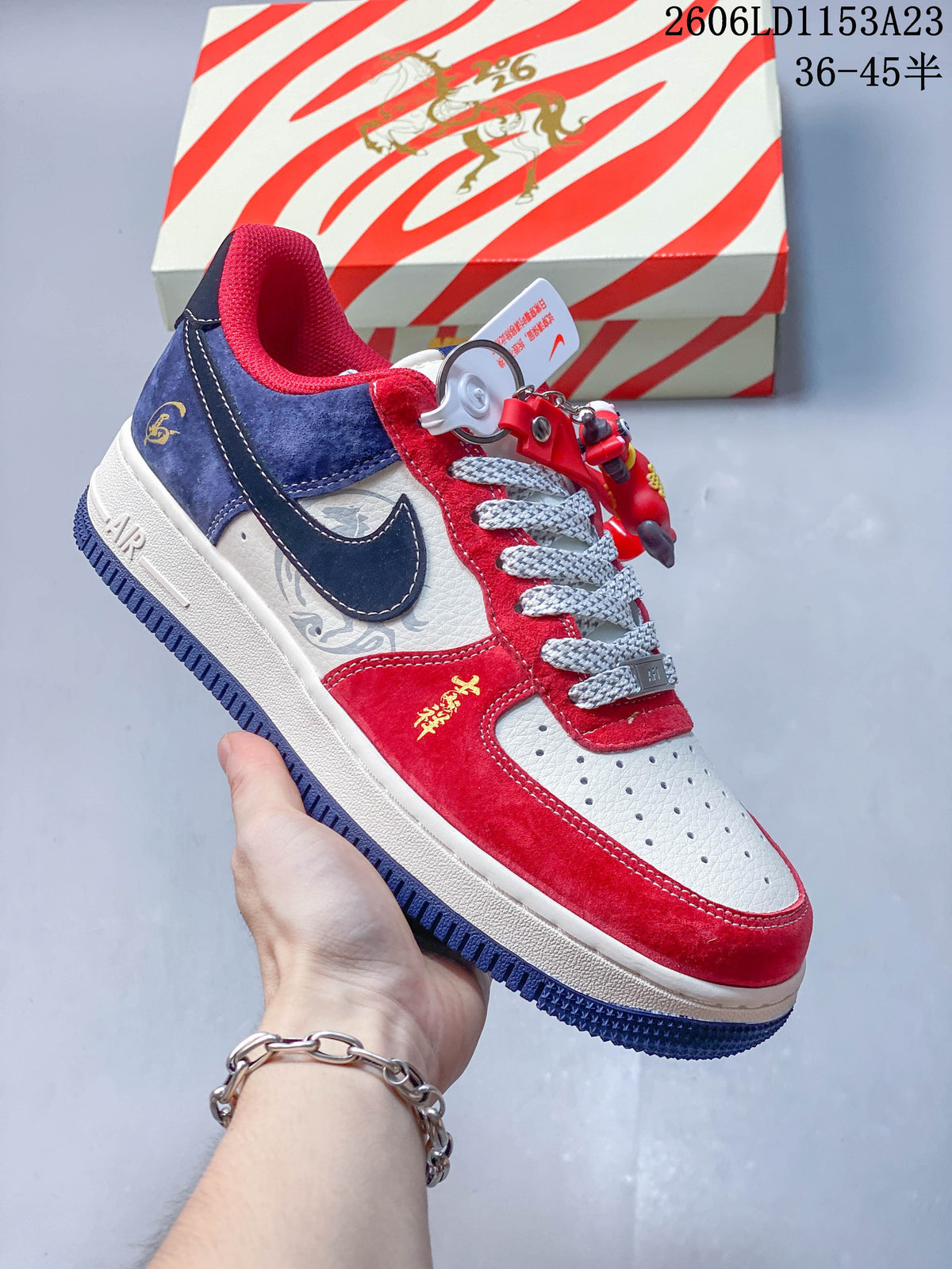 Close view of a red, white, and navy low-top sneaker with a side swoosh, patterned laces, and charm