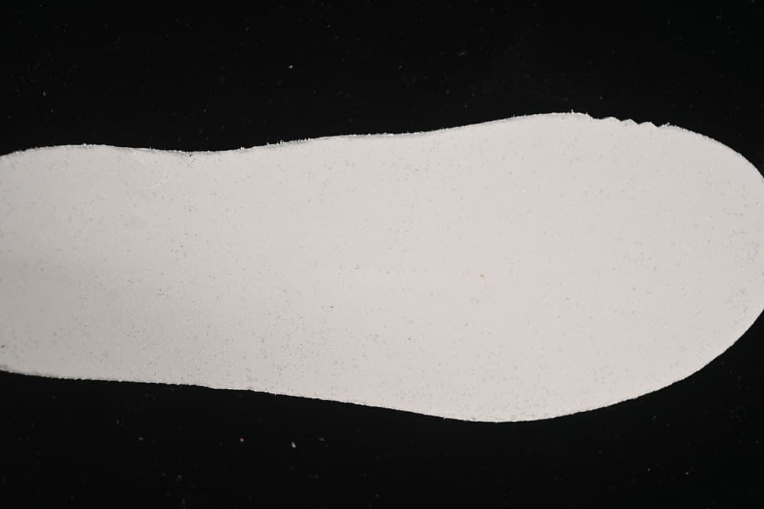 Close-up of a plain light-colored shoe-shaped surface.