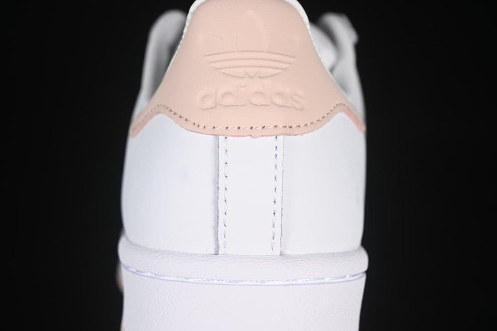 Rear view of the sneaker with blush-pink heel tab and embossed branding.