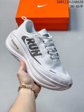 White Nike Vomero Plus shoe with large dark lettering and a light-colored layered sole.