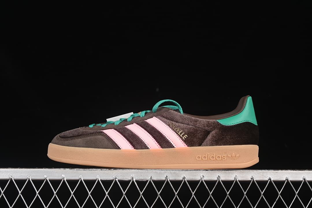 Side view of a dark brown adidas Gazelle Indoor sneaker with pink stripes, teal accents, and a gum-colored sole.