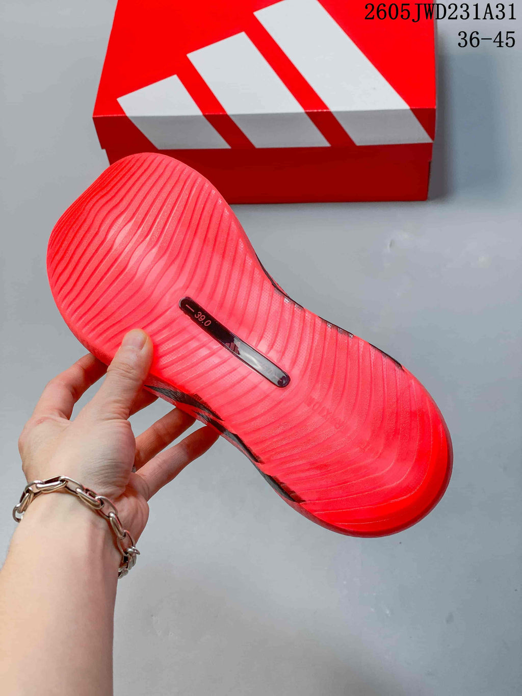 Underside of a bright pink shoe showing a ridged outsole and a visible size marking of 39.0.