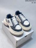 White and navy SMFK sneakers shown from the front on a box