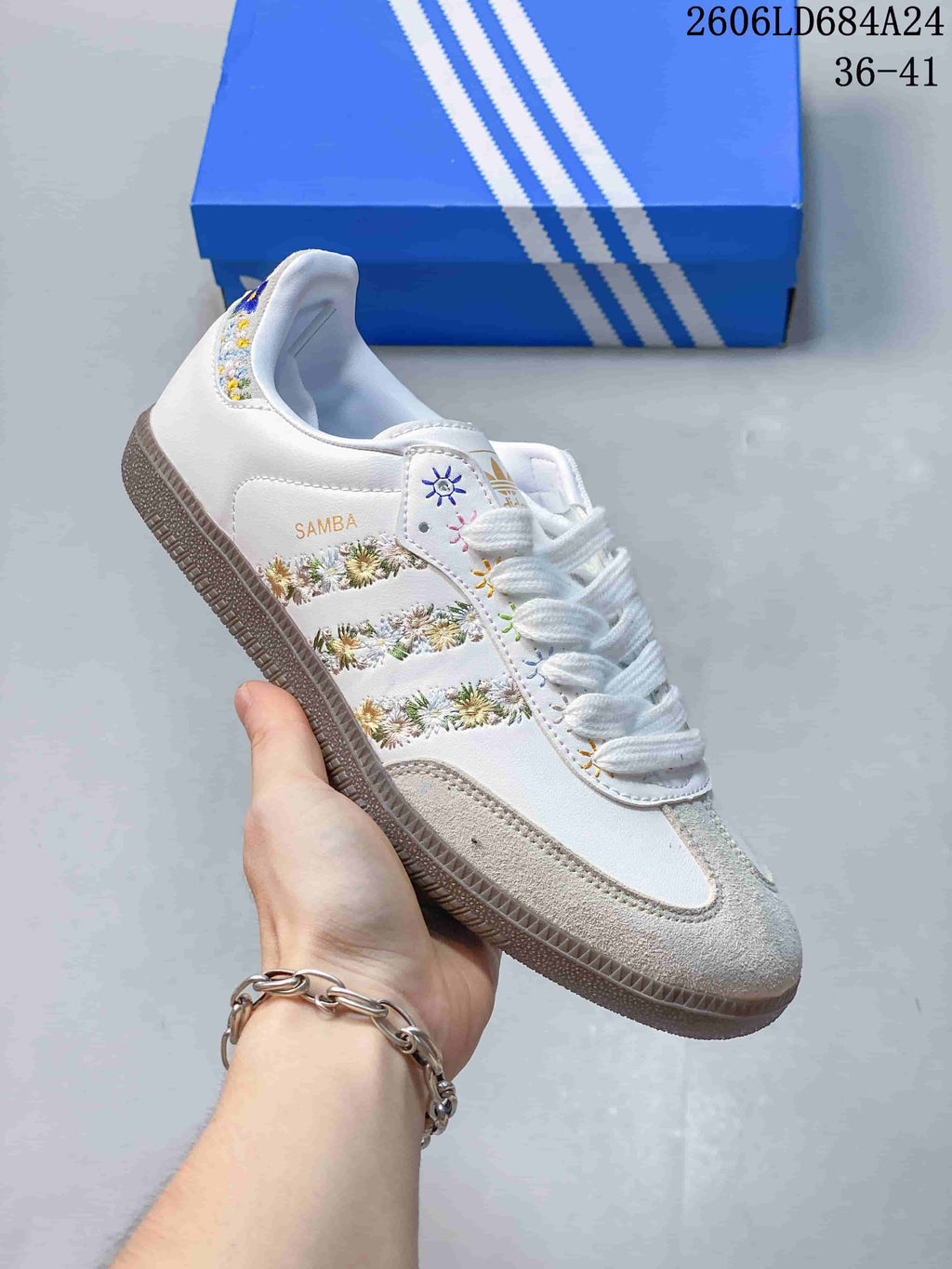 Close-up of a white Adidas Samba sneaker with floral side details and a suede-look toe overlay.