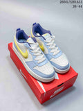 Pair of NikeCourt Borough Low Essential+ GS sneakers in white, light blue, yellow, and navy, shown on a red shoebox
