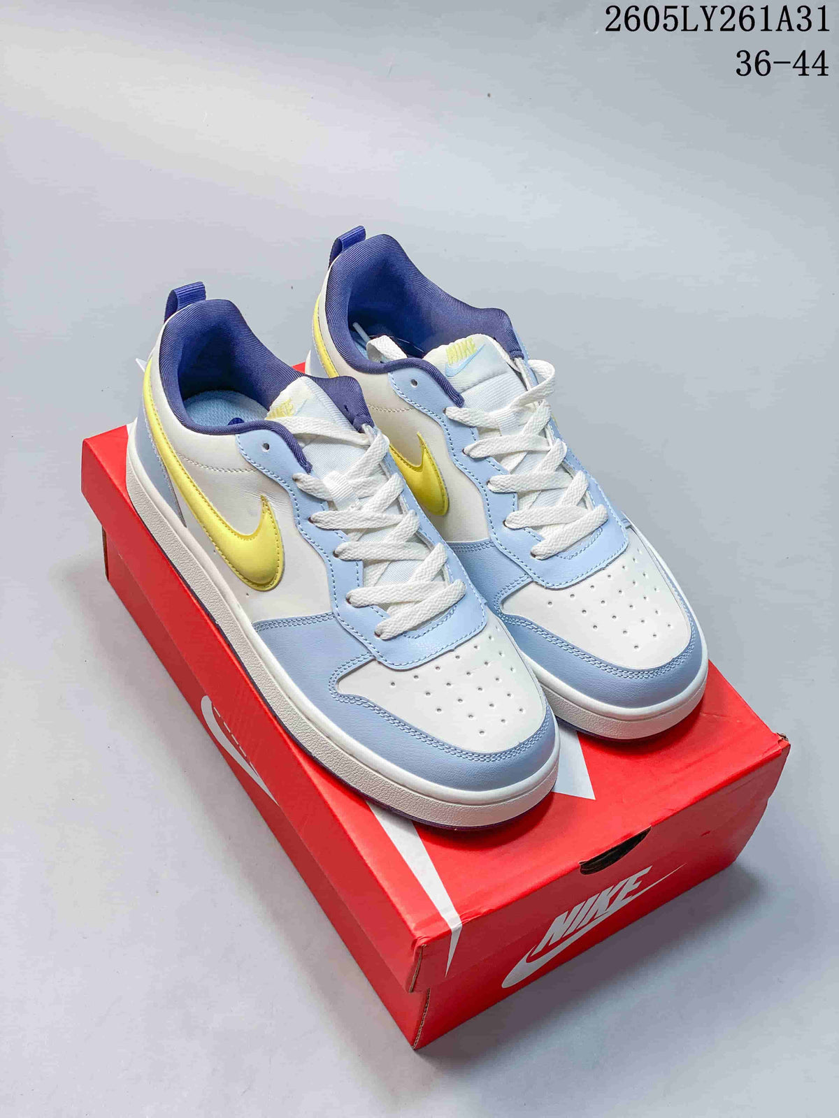 Pair of NikeCourt Borough Low Essential+ GS sneakers in white, light blue, yellow, and navy, shown on a red shoebox