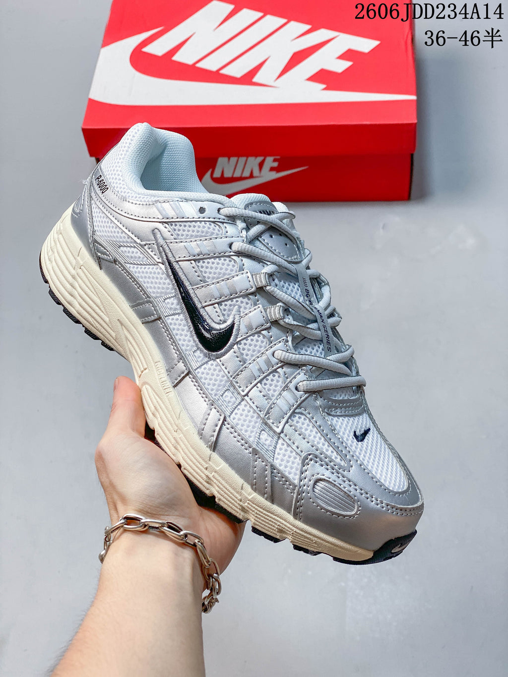 Angled side view of a silver Nike P-6000 sneaker with dark logo accents