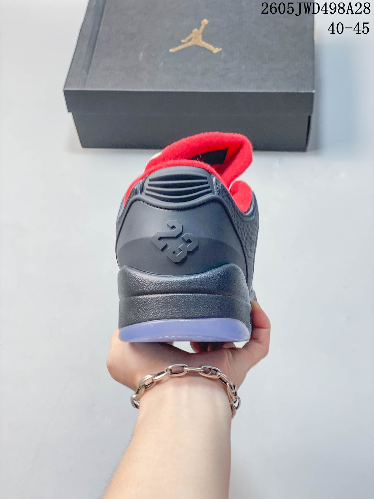Rear view of a dark Jordan low-top sneaker with red lining and a light-colored outsole edge.