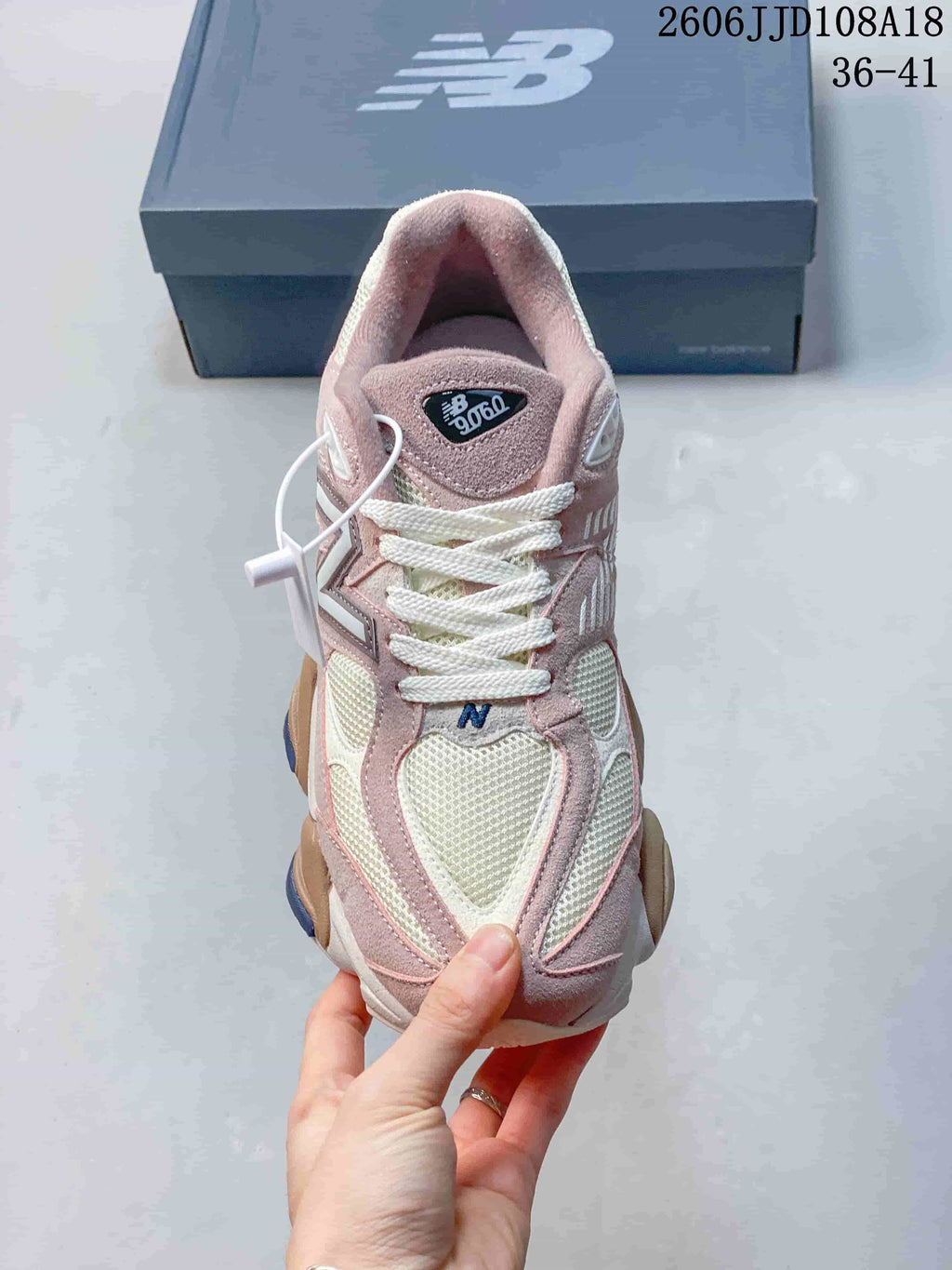 Front view of a pink and cream New Balance 9060 sneaker with white laces