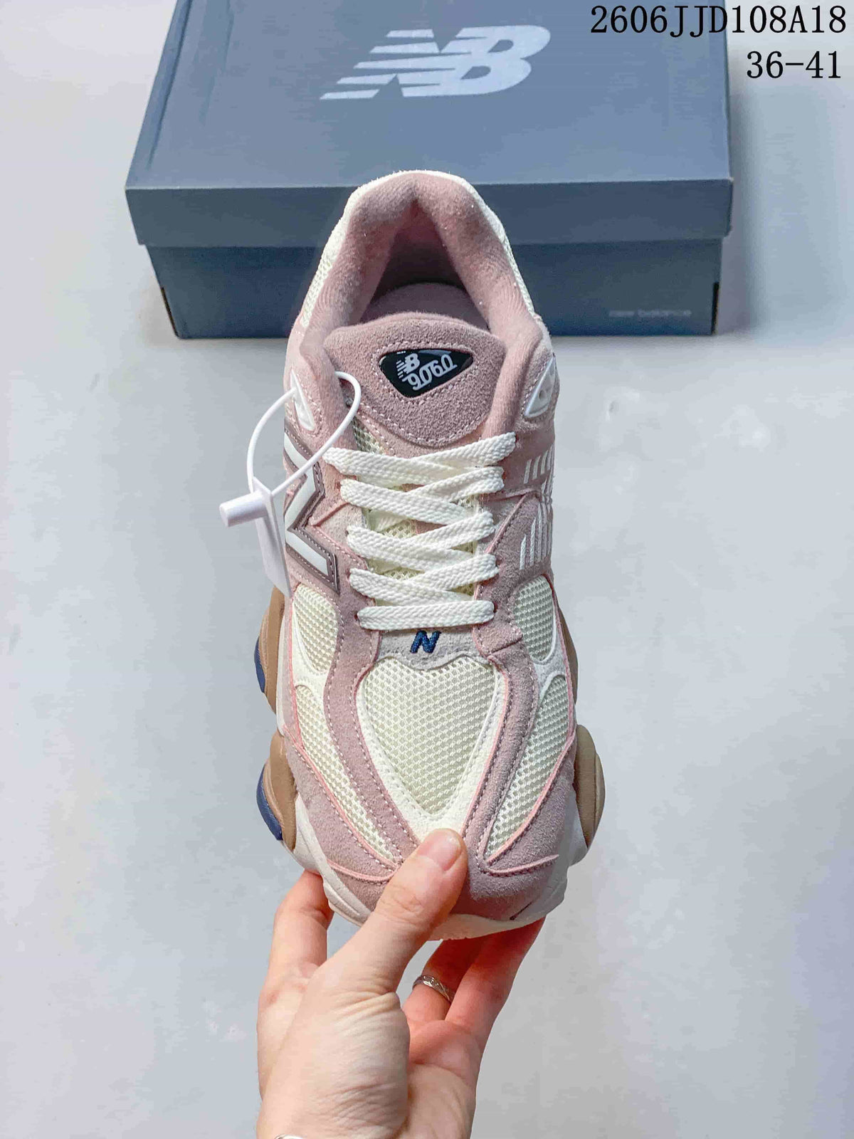 Front view of a pink and cream New Balance 9060 sneaker with white laces