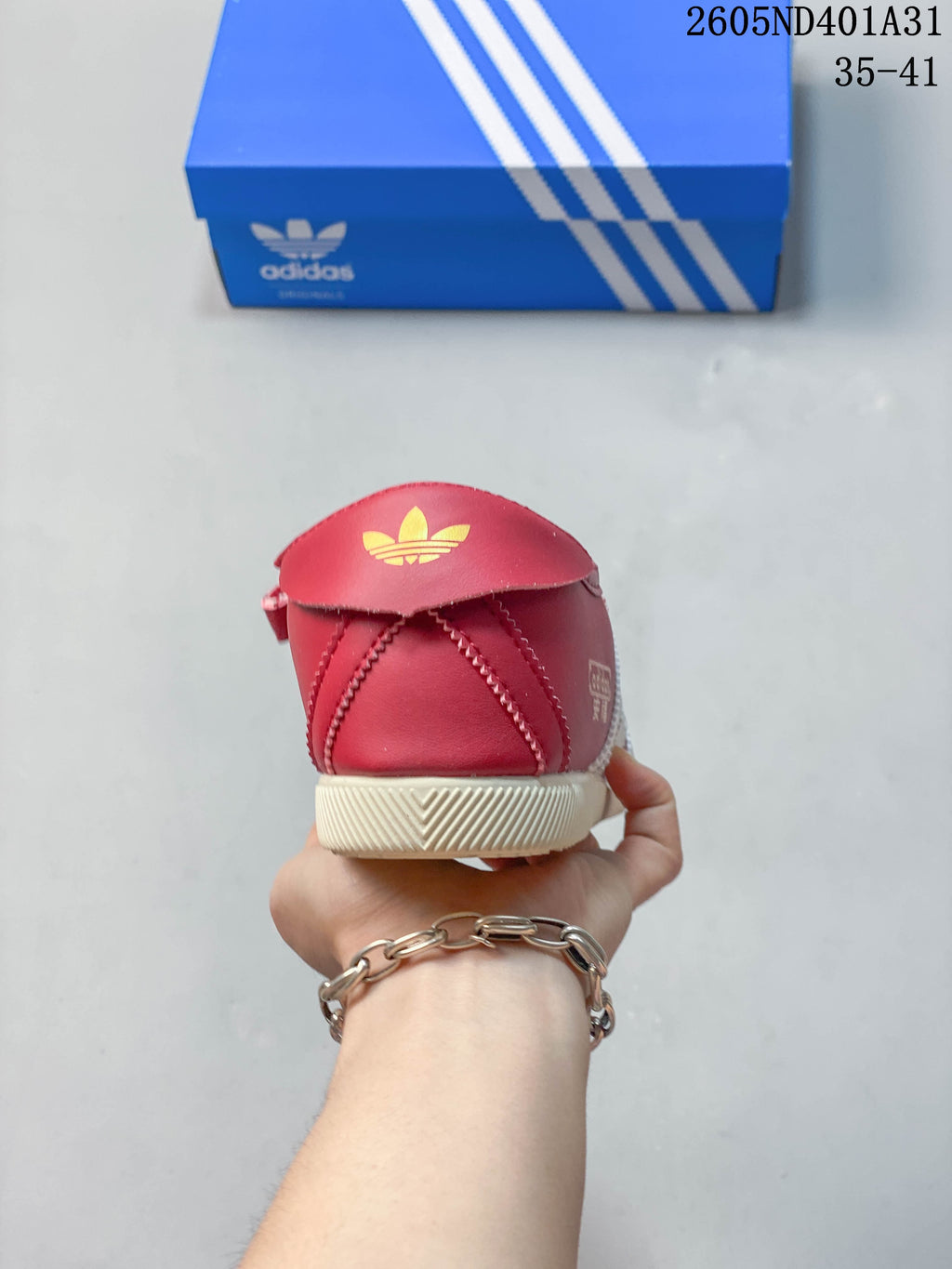 Rear view of the red sneaker with trefoil detail and cream outsole