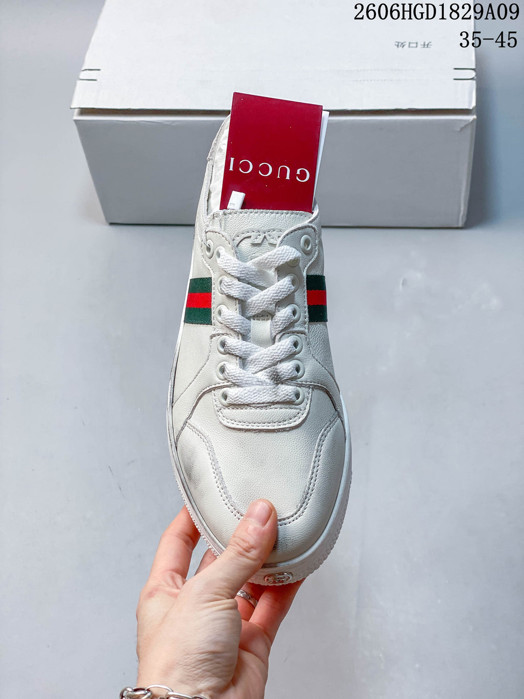Front view of a white lace-up sneaker with a red-and-green stripe detail.