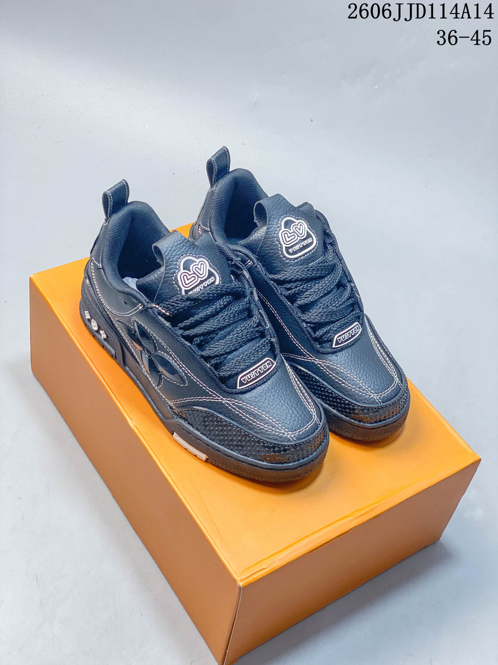 Pair of charcoal Louis Vuitton Trainer low-top sneakers displayed on an orange shoebox