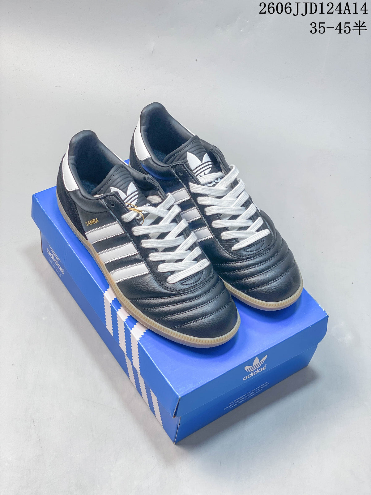 Pair of dark blue adidas Samba sneakers with white stripes and laces, shown on a blue shoebox