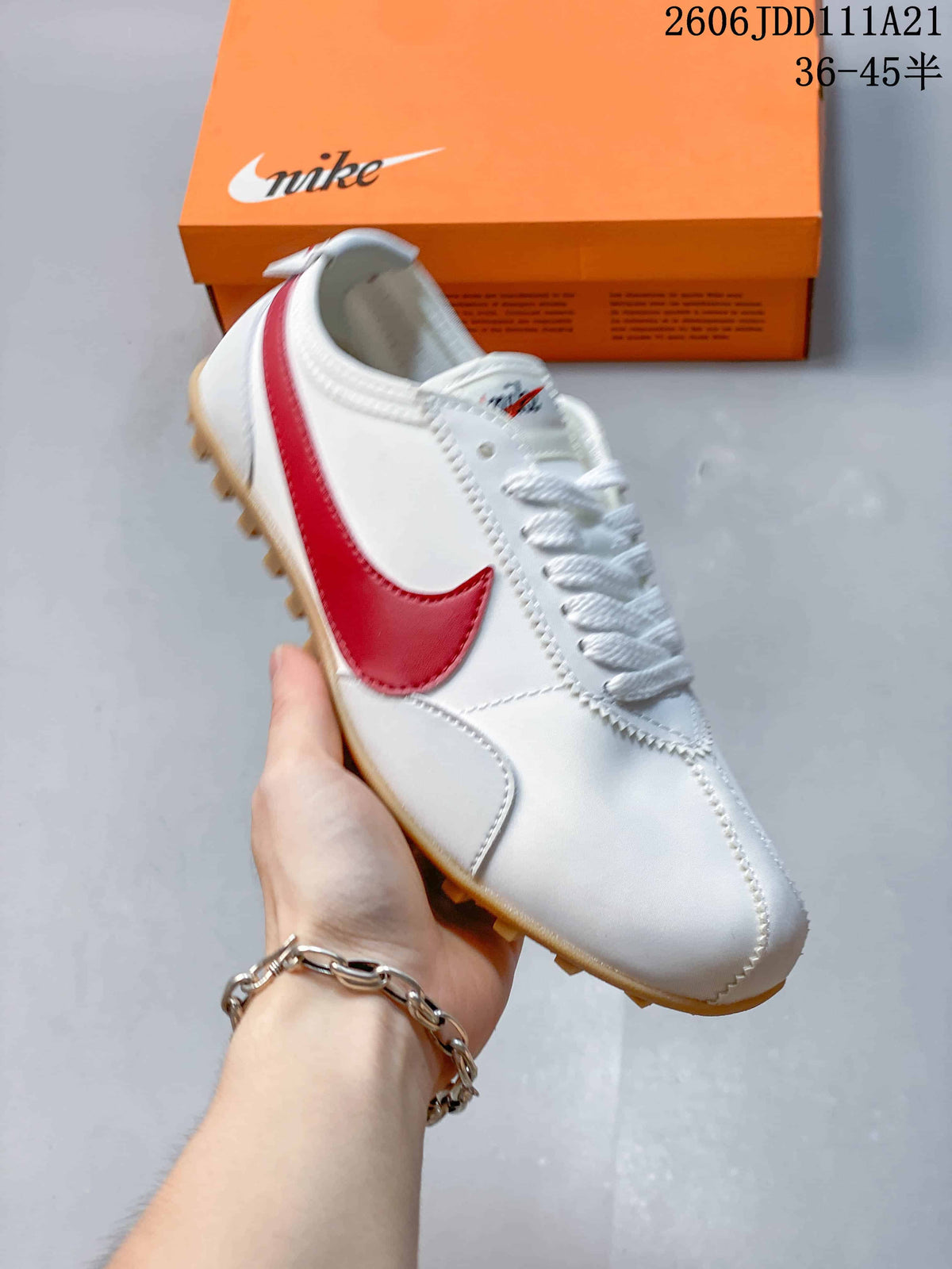 Angled view of a white low-top sneaker with red side detailing and gum-colored outsole