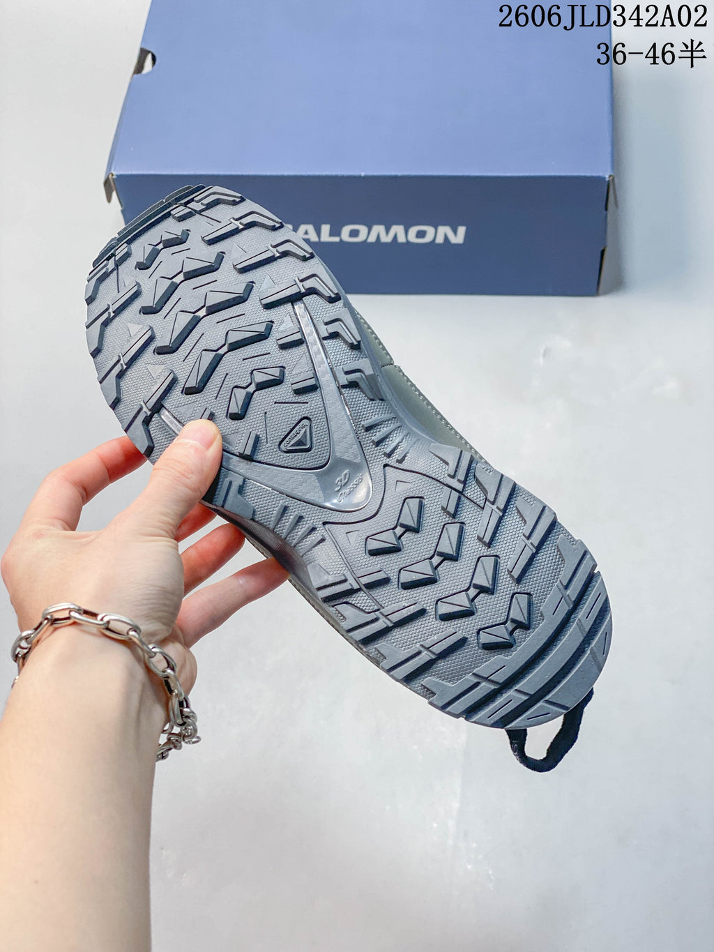Close view of the lugged outsole on a gray Salomon trail shoe.
