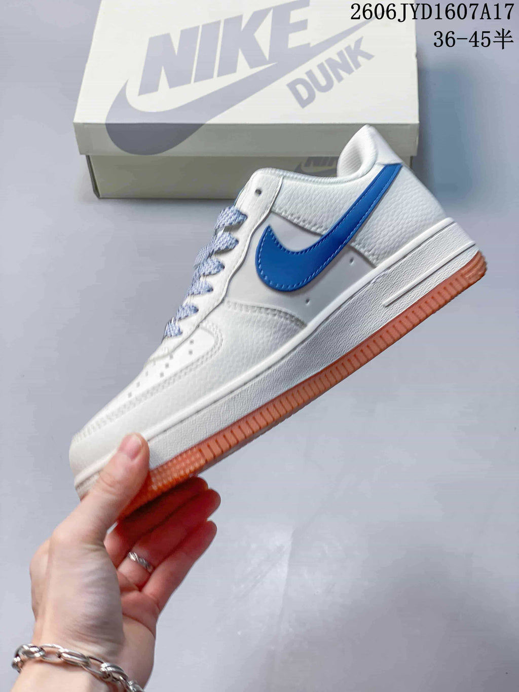 Side view of the white low-top sneaker with a blue Swoosh and gum-colored outsole