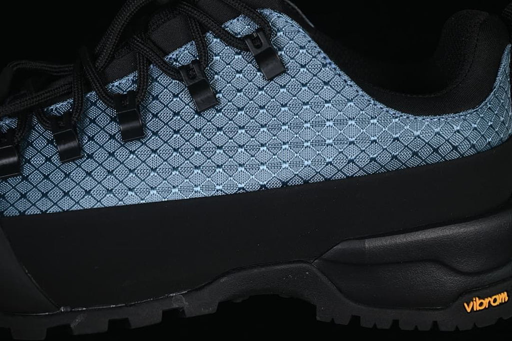 Close-up of the patterned side panels, black overlay, laces and outsole.