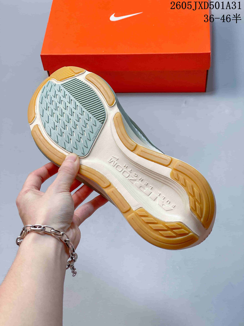Underside of a running shoe showing a patterned grey outsole center and gum-colored rubber sections