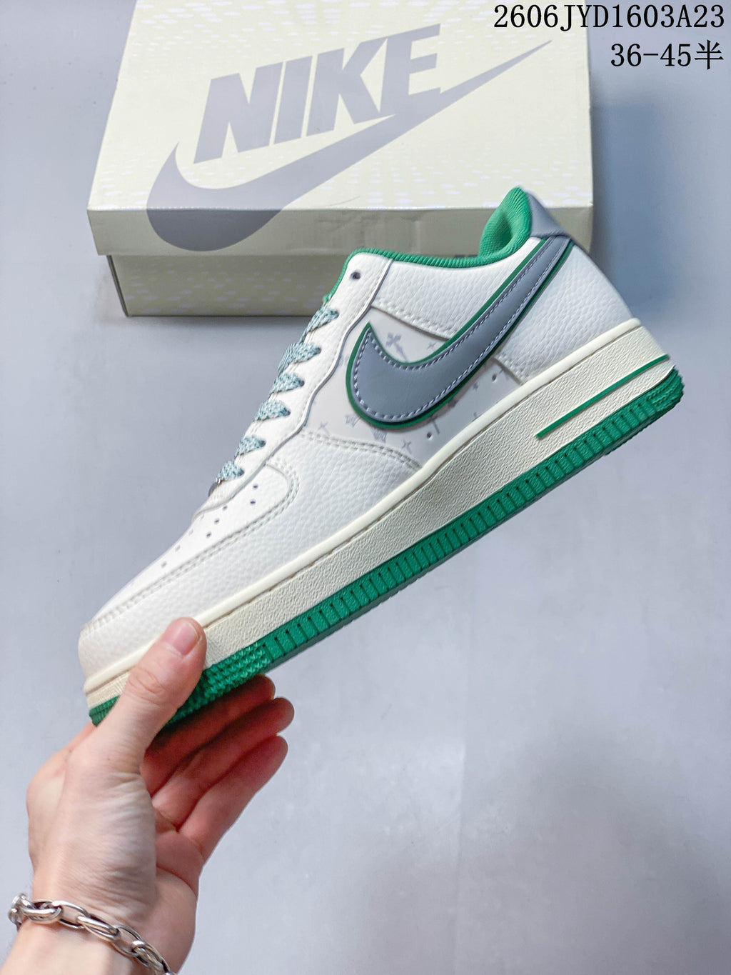 Side view of the white low-top sneaker with gray side panel and green trim.
