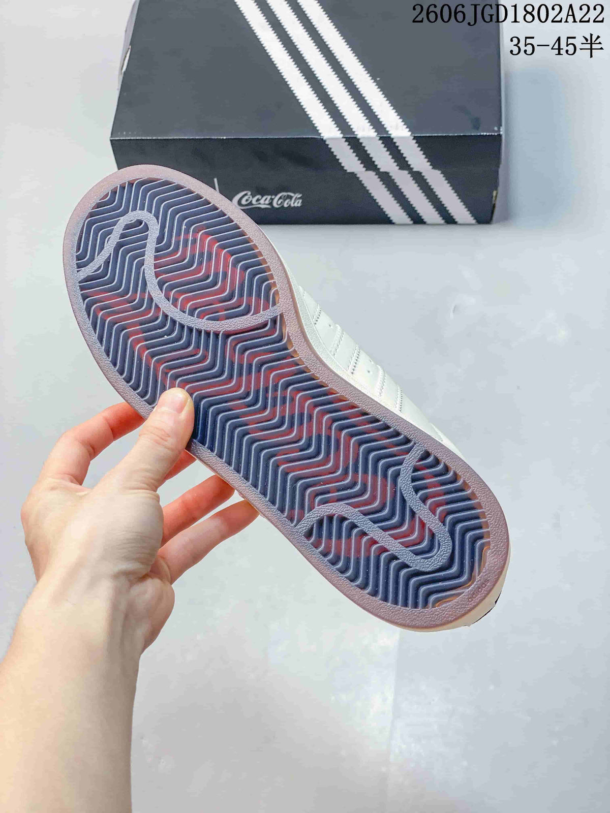 Close-up of the sneaker outsole with a patterned tread and branded box in the background.