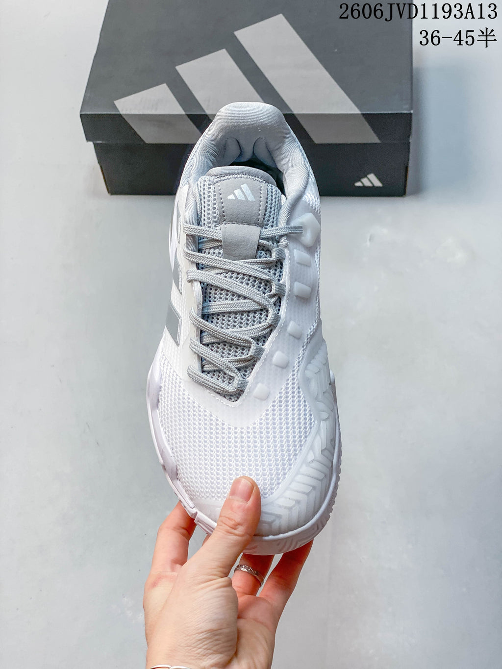 Top view of a white and silver lace-up Adidas tennis shoe