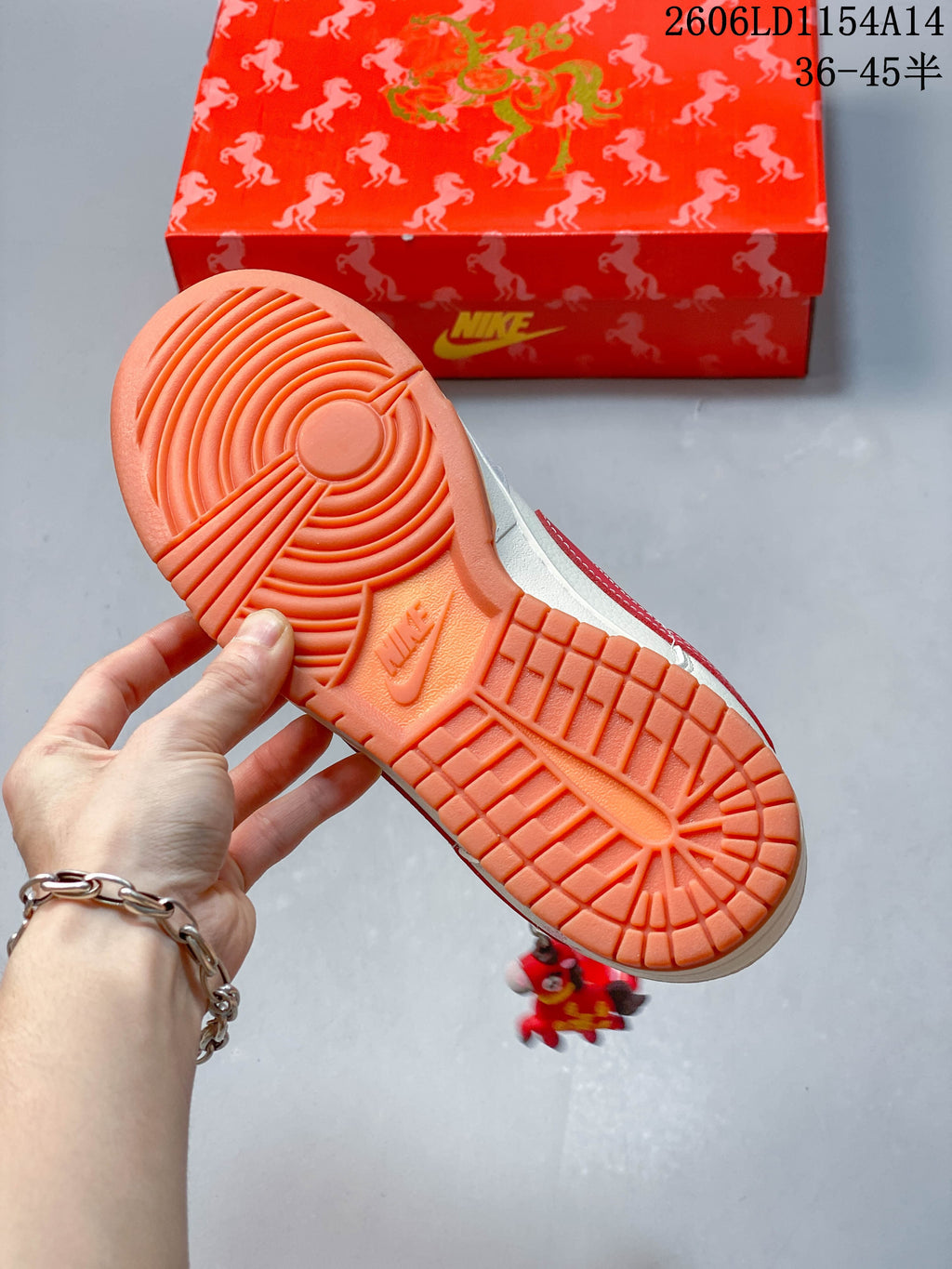 Close-up of the orange outsole on an off-white and red low-top sneaker, with a red patterned shoe box behind it.