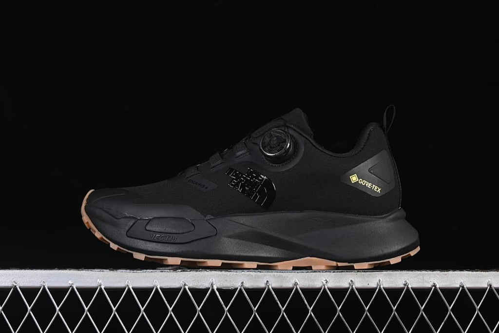 Side view of a black The North Face Vectiv Enduris Low shoe with tan-toned outsole lugs.