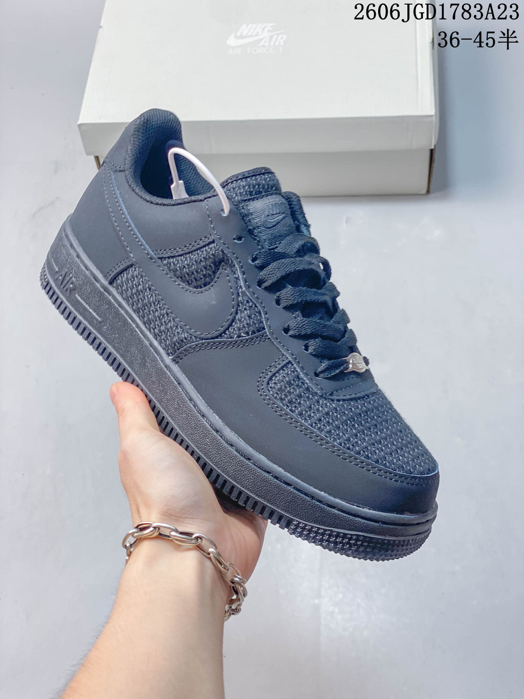 Angled side view of a dark gray low-top sneaker with textured panels and a lace ornament.