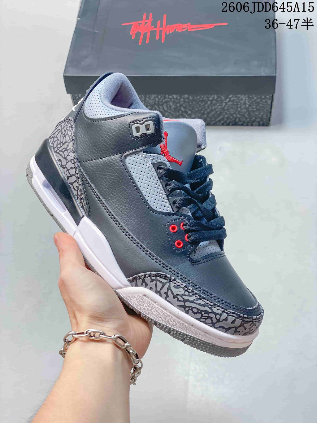 Close side view of a grey mid-top sneaker with elephant-print overlays, dark laces, and red accents.