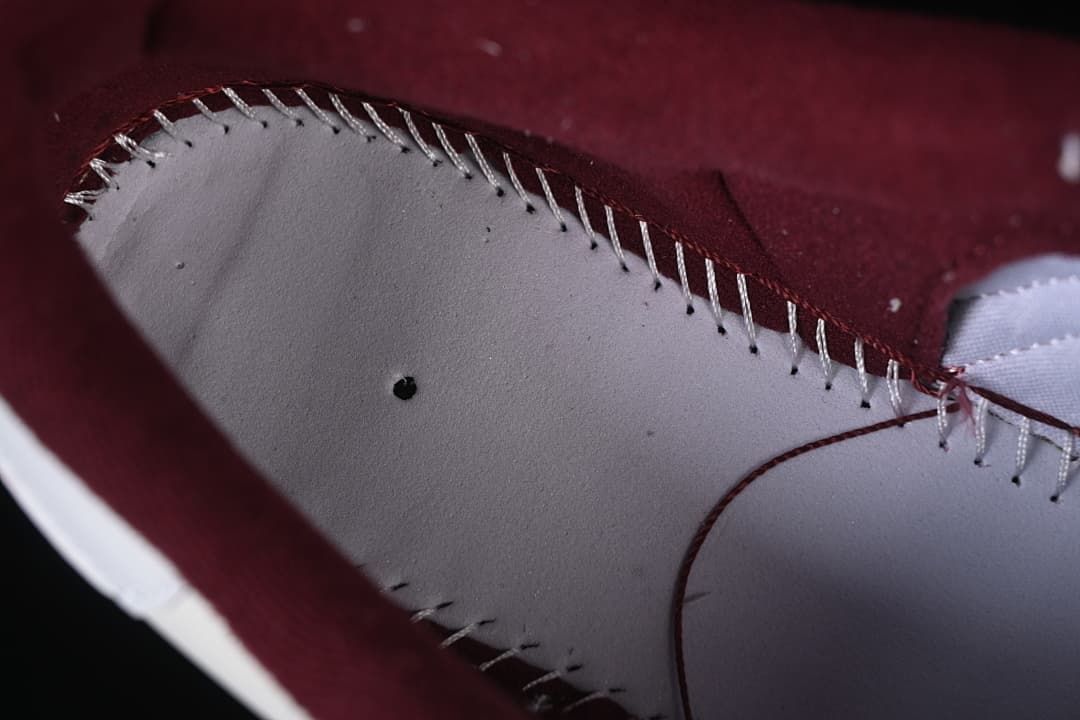 Close-up of stitching and construction along the burgundy and white shoe interior.