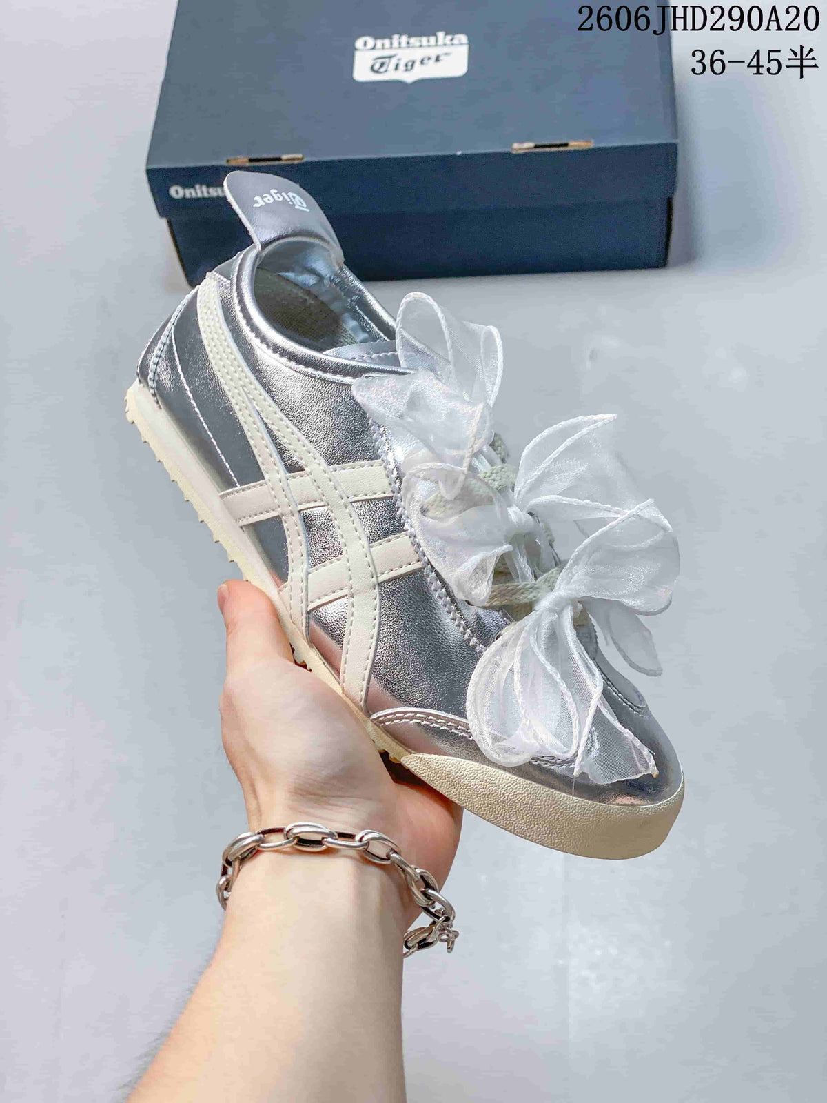 Angled side view of a silver Onitsuka Tiger sneaker with cream stripes and ribbon laces