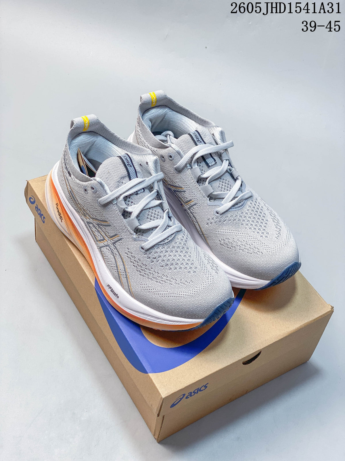 Pair of light gray ASICS GEL-NIMBUS 26 running shoes with orange and navy accents, displayed on a shoebox