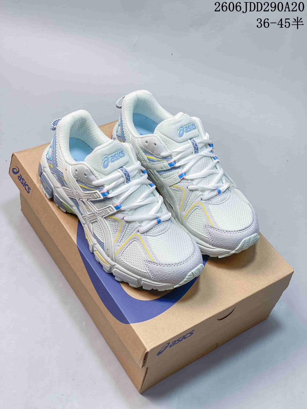 Pair of light-colored ASICS Gel-Kahana 8 shoes with lavender, blue, and yellow accents on a shoe box.
