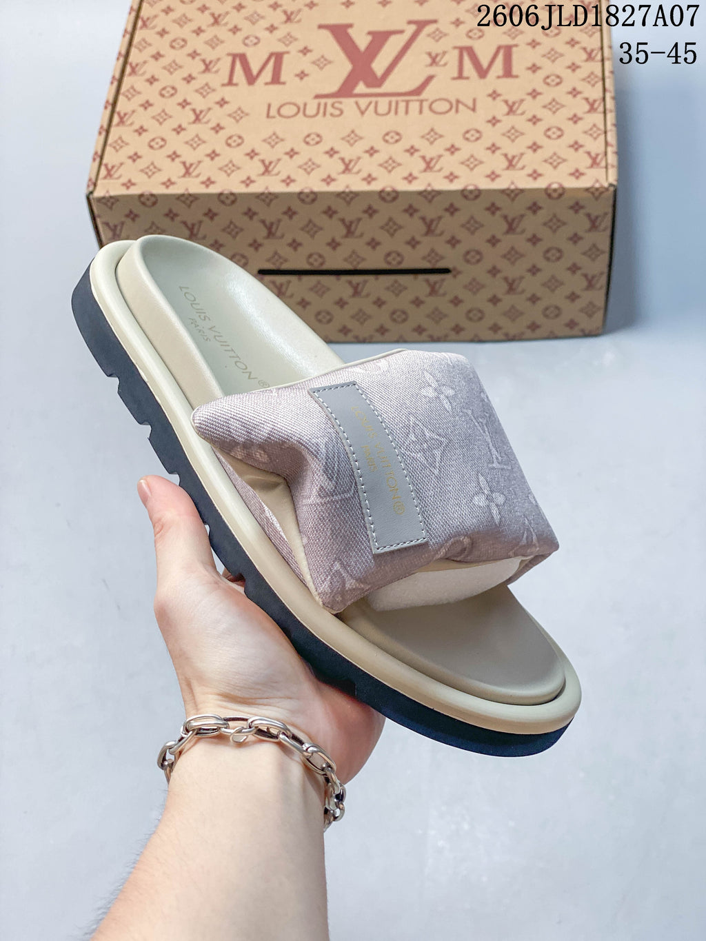 Angled view of a pale pink monogram slide sandal with a contrasting outsole