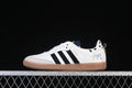 Side view of white adidas Samba OG sneakers with black stripes, gray toe overlay, gum outsole, spotted heel detail, and character artwork.