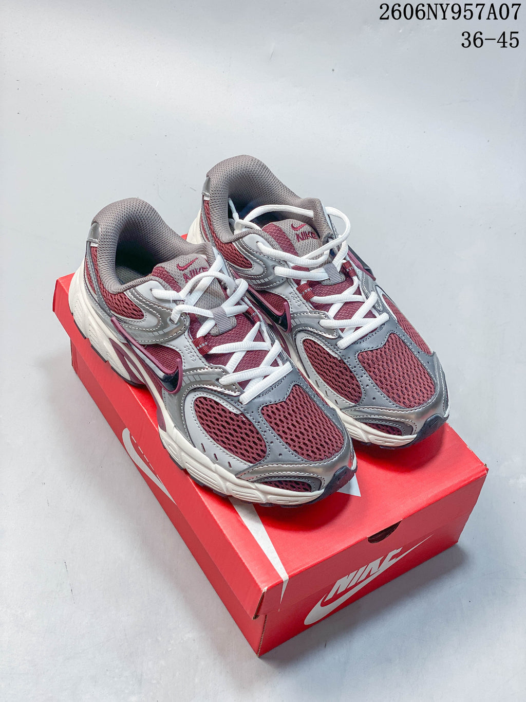 Pair of burgundy, silver, gray, and white Nike V5 RNR sneakers on a shoebox.