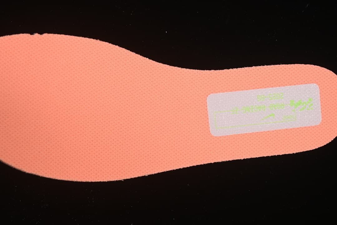 Close-up of the coral-orange textured insole and printed label.