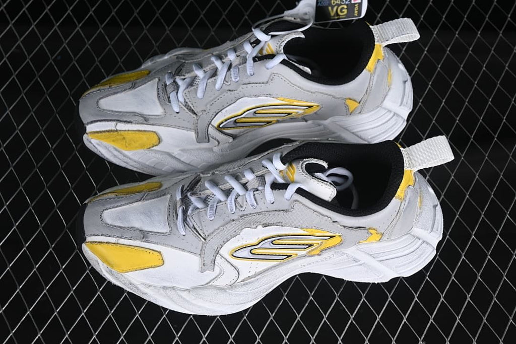 Pair of grey, white and yellow low-top sneakers viewed from above