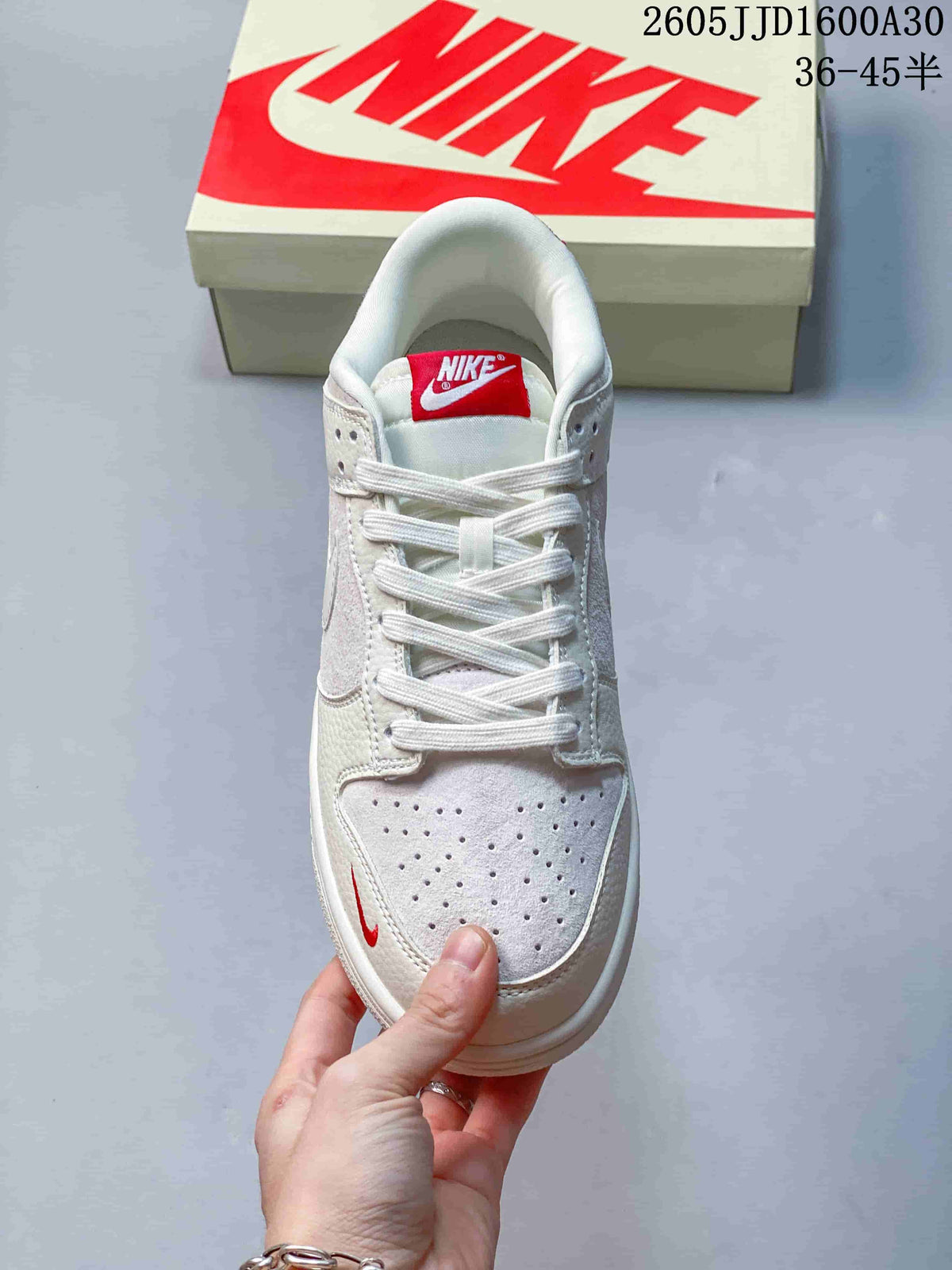 Front view of an off-white low-top sneaker with red tongue branding and perforated toe